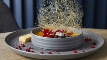 A dessert in a bowl on a plate, with a decorative spider web and berries.