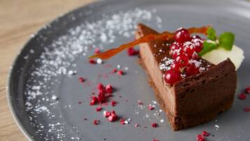 A slice of chocolate cake with berries and mint leaves on a plate.