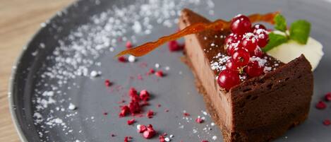 Una fetta di torta al cioccolato con frutti di bosco e foglie di menta su un piatto.