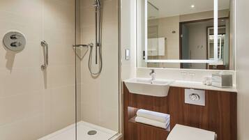 A modern bathroom with a glass-enclosed shower, a vanity with a sink, and a toilet.