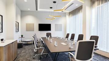 A conference room with a long table, chairs, a TV, and a modern ceiling design.