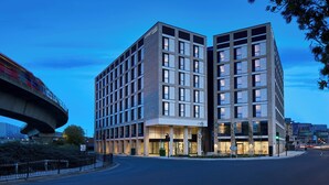 Un hotel moderno con una entrada destacada, varios pisos y una amplia fachada de vidrio.