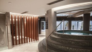 A modern indoor pool area with a spiral staircase leading to a hot tub. - Four Points by Sheraton Prishtina City (Preoce)