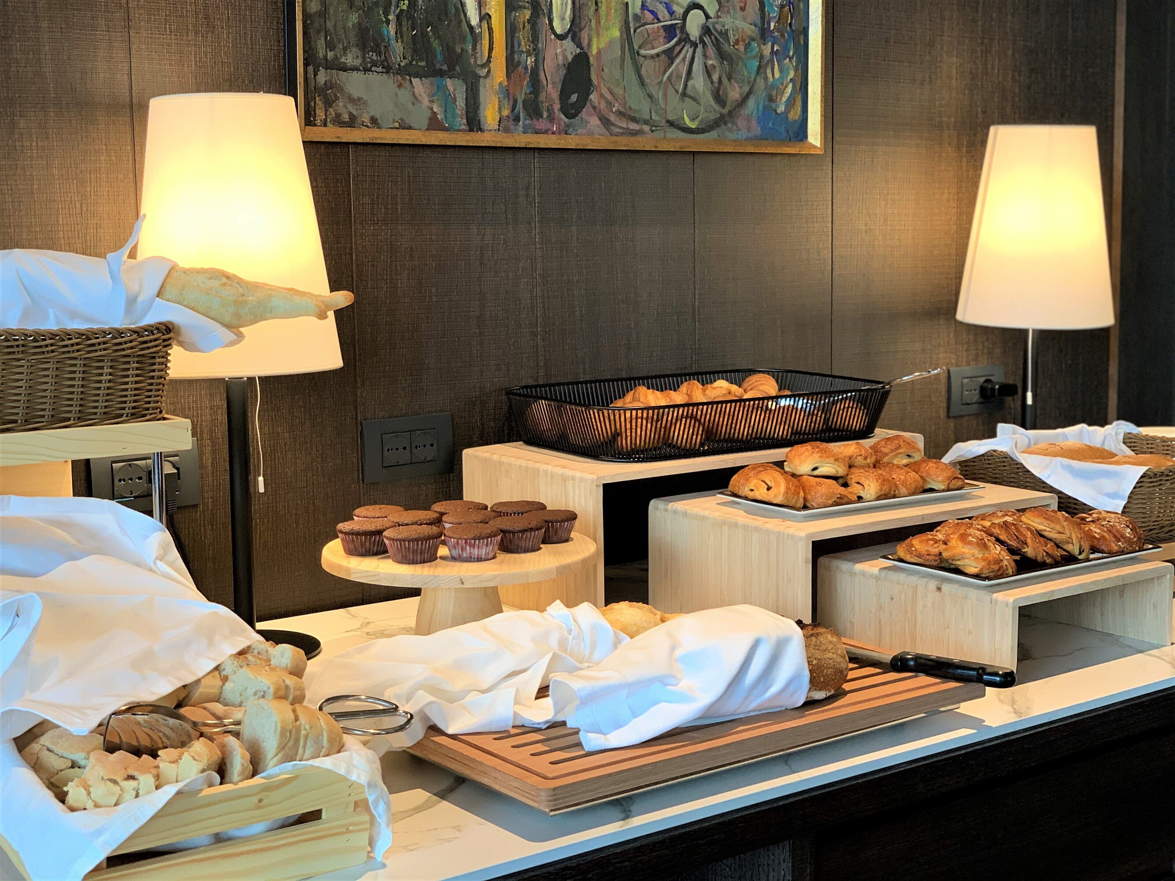 A breakfast buffet with various pastries, bread, and muffins.