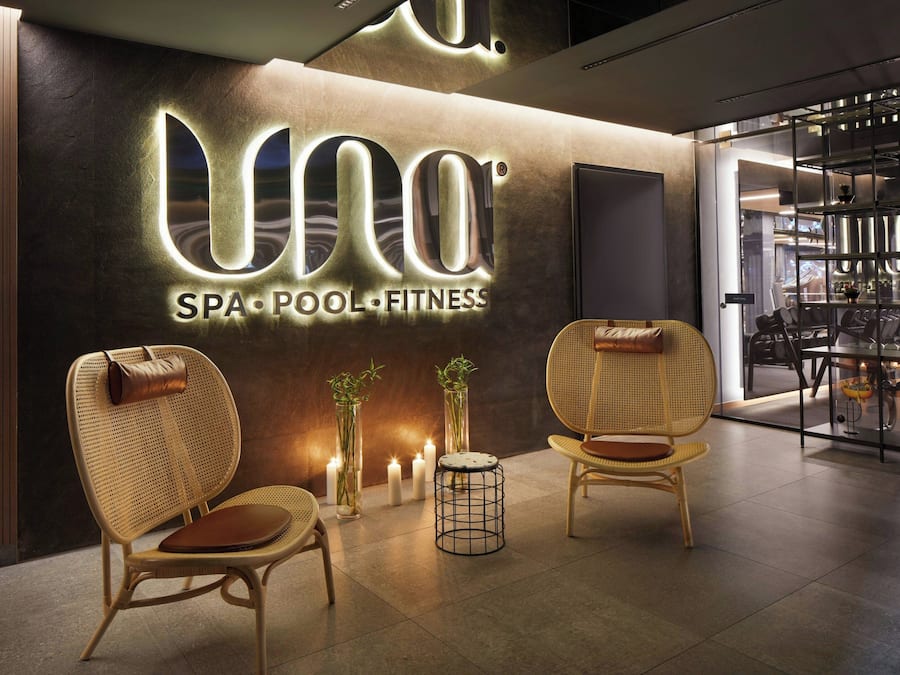A spa, pool, and fitness center interior with wicker chairs, candles, and a modern sign.