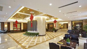 A hotel lobby with a central column, seating area, and decorative plants. - Ningbo Sunny Hotel (Ningbo)