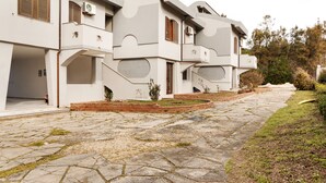 A modern building with a stone-paved entrance, a brick pathway, and a small garden area. - Altramonto House (Siracusa)