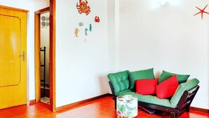 A room with a green sofa, a wooden door, and a tiled floor. - Altramonto House (Siracusa)