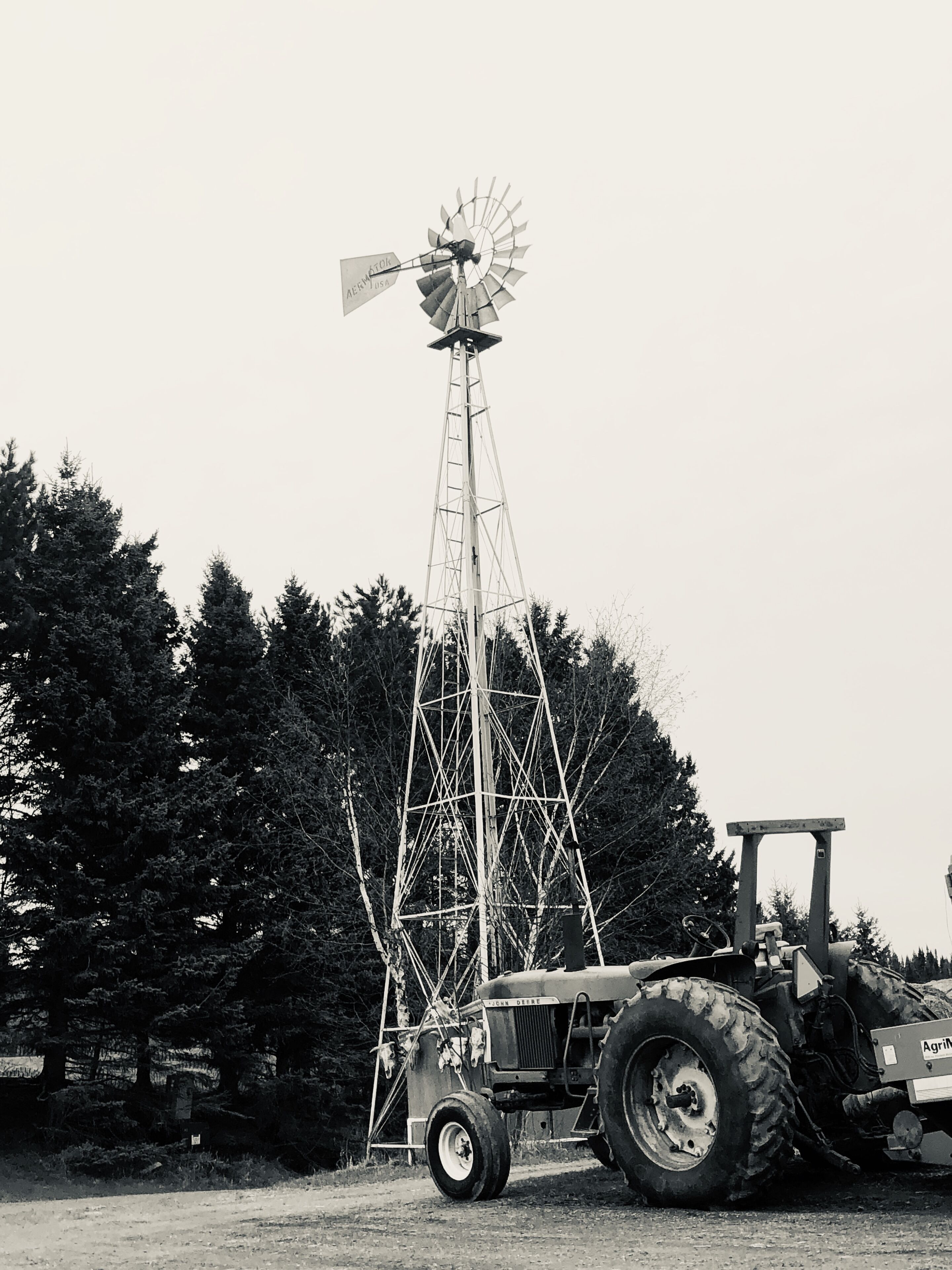 A windmill with a tractor parked nearby.