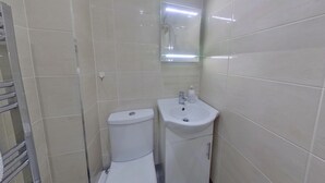 A small bathroom with a toilet and a sink, both in white. - Victoria House - Classic Studio by CovStays (Coventry)