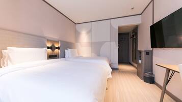Quarto de hotel moderno com uma cama grande, televisão e uma mesinha.