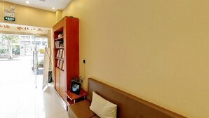 A reception area with a sofa, a bookshelf, and a TV on a small table. - Hanting Hotel (Shanghai)