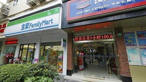 A storefront with a sign for 'HANTING EXPRESS' and a 'FamilyMart' store across the street. - Hanting Hotel (Shanghai)