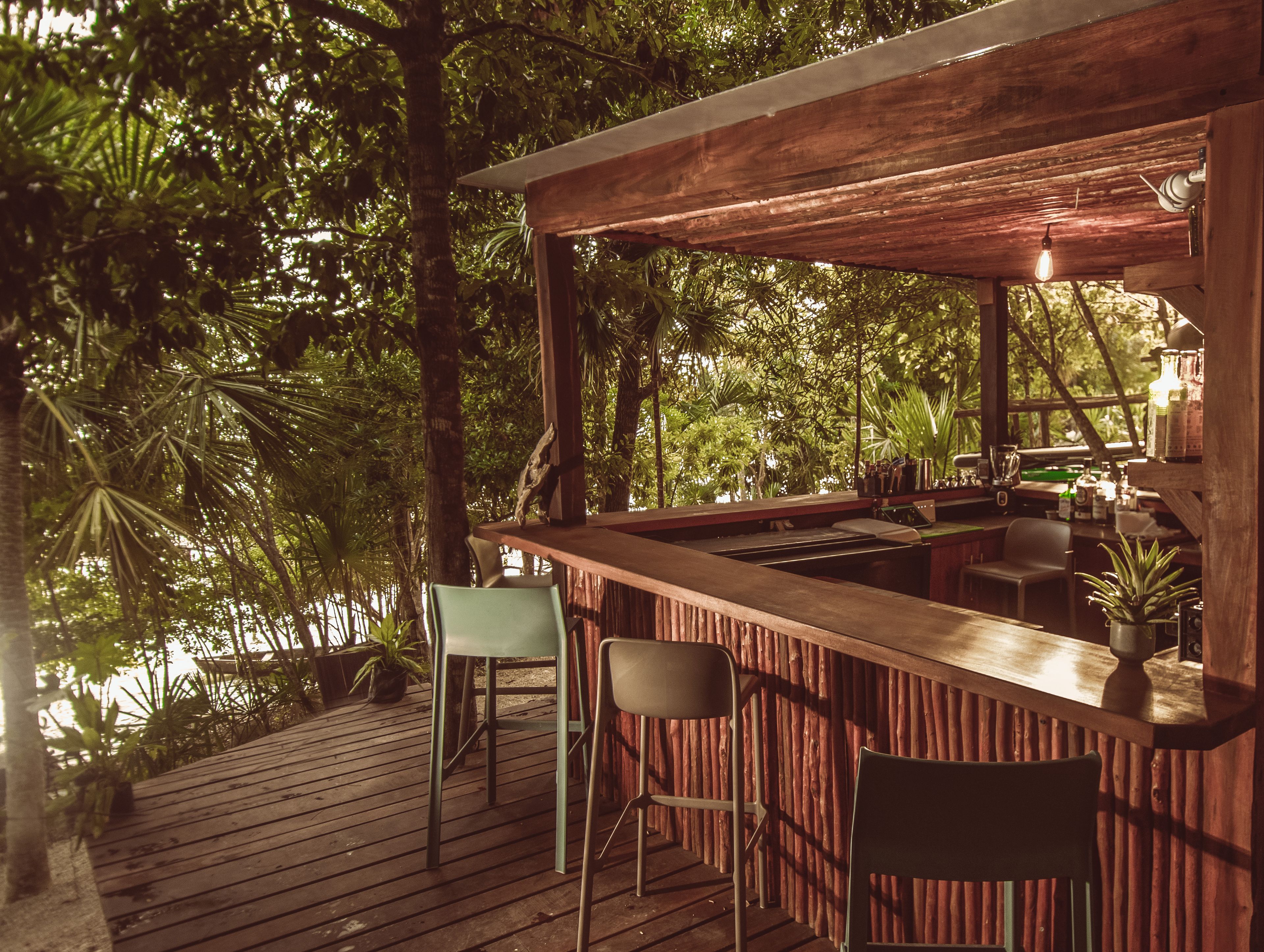 Una terraza de madera con una zona de bar, dos sillas y vistas a un follaje exuberante.