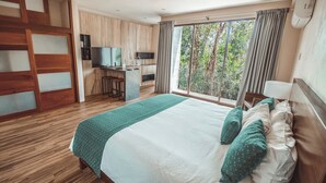 Una habitación de hotel con una cama grande, un escritorio con silla, un televisor y una ventana con cortinas.
