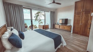 Un dormitorio con una cama grande, televisor, armario de madera y balcón con vistas.