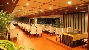 A restaurant with a long table layout, wooden flooring, and a warm ambiance. - Chonpines Hotel (Dalian)
