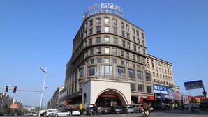A multi-story hotel with a curved facade, signage indicating it is a Chinatown hotel, and a clear blue sky in the background. - Chonpines Hotel (Dalian)