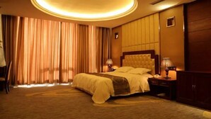 A hotel room with a large bed, two bedside tables, a headboard, and a circular ceiling light. - Chonpines Hotel (Dalian)
