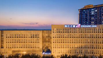 A hotel building with a modern facade, multiple floors, and a prominent signage for 'Jianjiang Inn'.