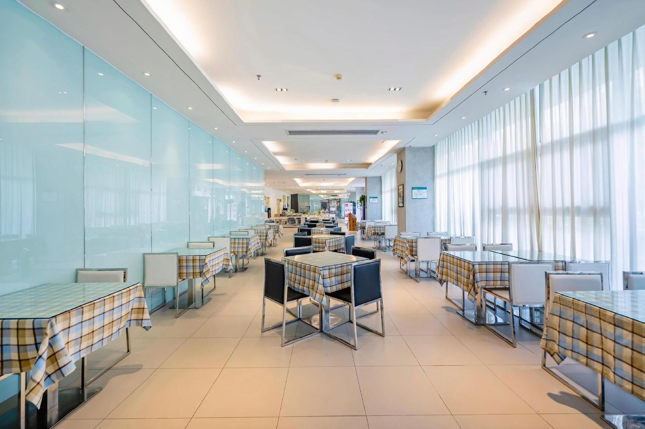 A modern restaurant with glass partitions, metal tables, and chairs.