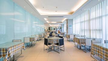 A modern restaurant with glass partitions, metal tables, and chairs.
