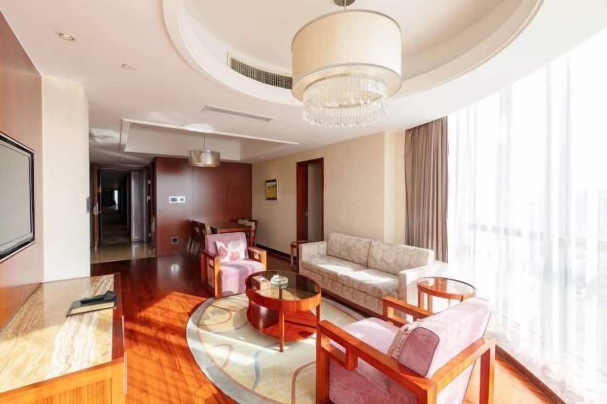 A modern hotel room with a curved seating area, a large chandelier, and a view of the city.