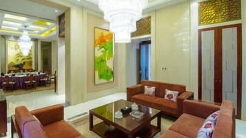 A hotel lobby with a reception desk, seating area, and a dining area.