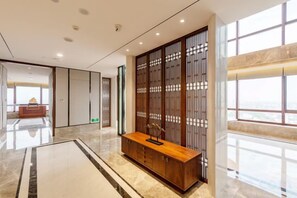 A modern hotel lobby with a wooden reception desk, a large window with a view, and a traditional-style partition. - Dongdu Narada Grand Hotel (Yixing)