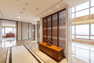 Un moderno vestíbulo de hotel con un mostrador de recepción de madera, un amplio ventanal con vistas y un separador de estilo tradicional.