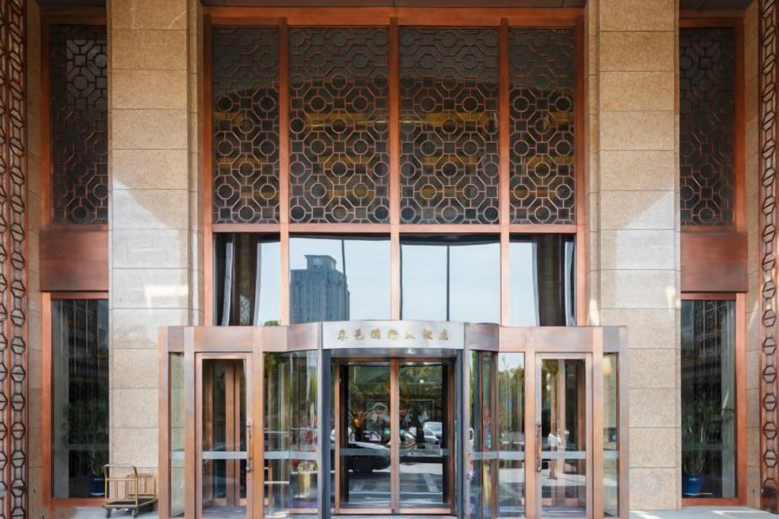 A building entrance with a glass door, a metal frame, and a patterned wall above.