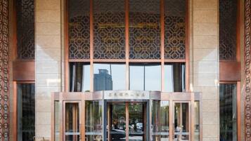 A building entrance with a glass door, a metal frame, and a patterned wall above.