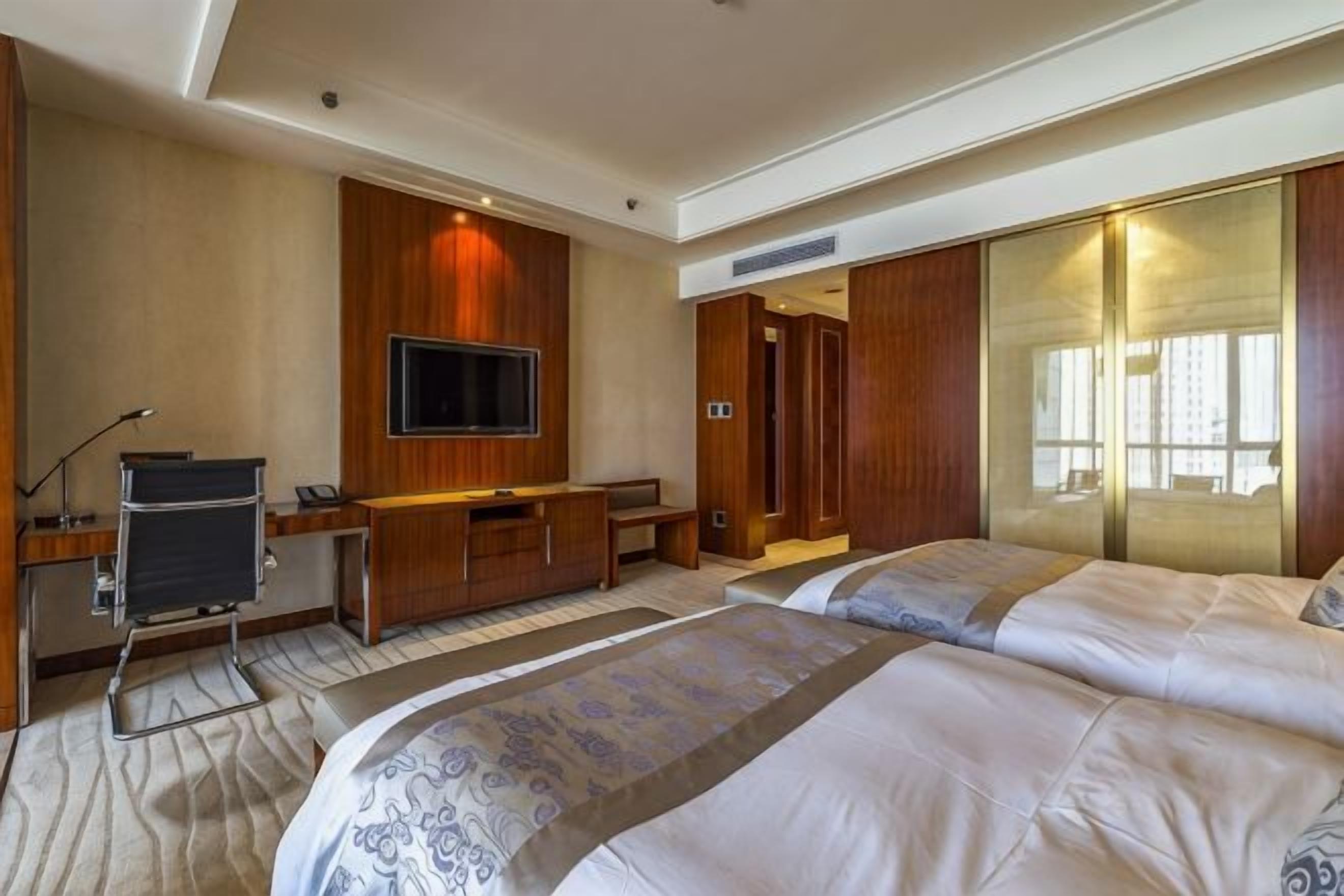A hotel room with a bed, a desk, a television, and a wardrobe.