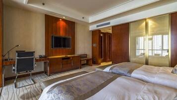 A hotel room with a bed, a desk, a television, and a wardrobe.