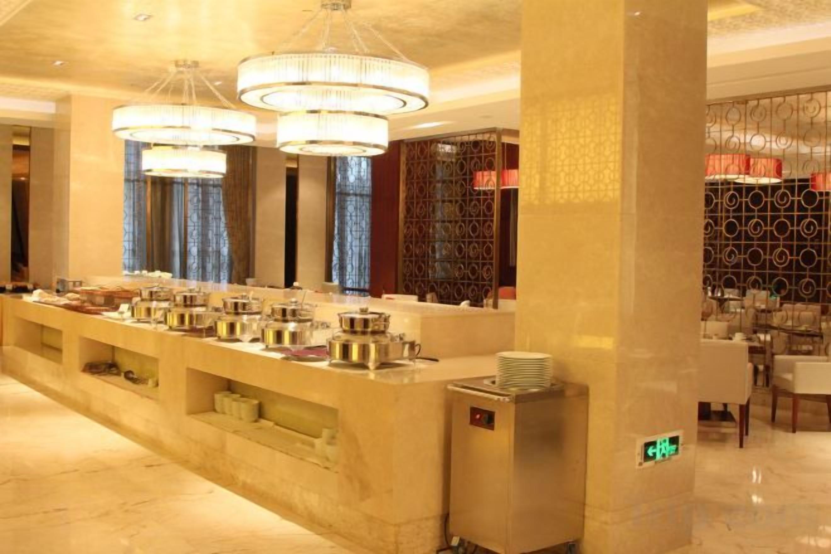 Un espace buffet avec plusieurs points de service, un comptoir d’accueil et un coin salon avec des tables et des chaises.