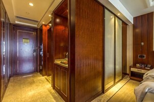Una habitación de hotel con un armario de madera, una mesita de noche pequeña y una cama.