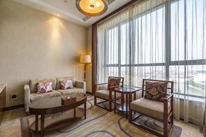 A hotel room with a sofa, armchairs, a coffee table, and a large window with curtains. - Dongdu Narada Grand Hotel (Yixing)