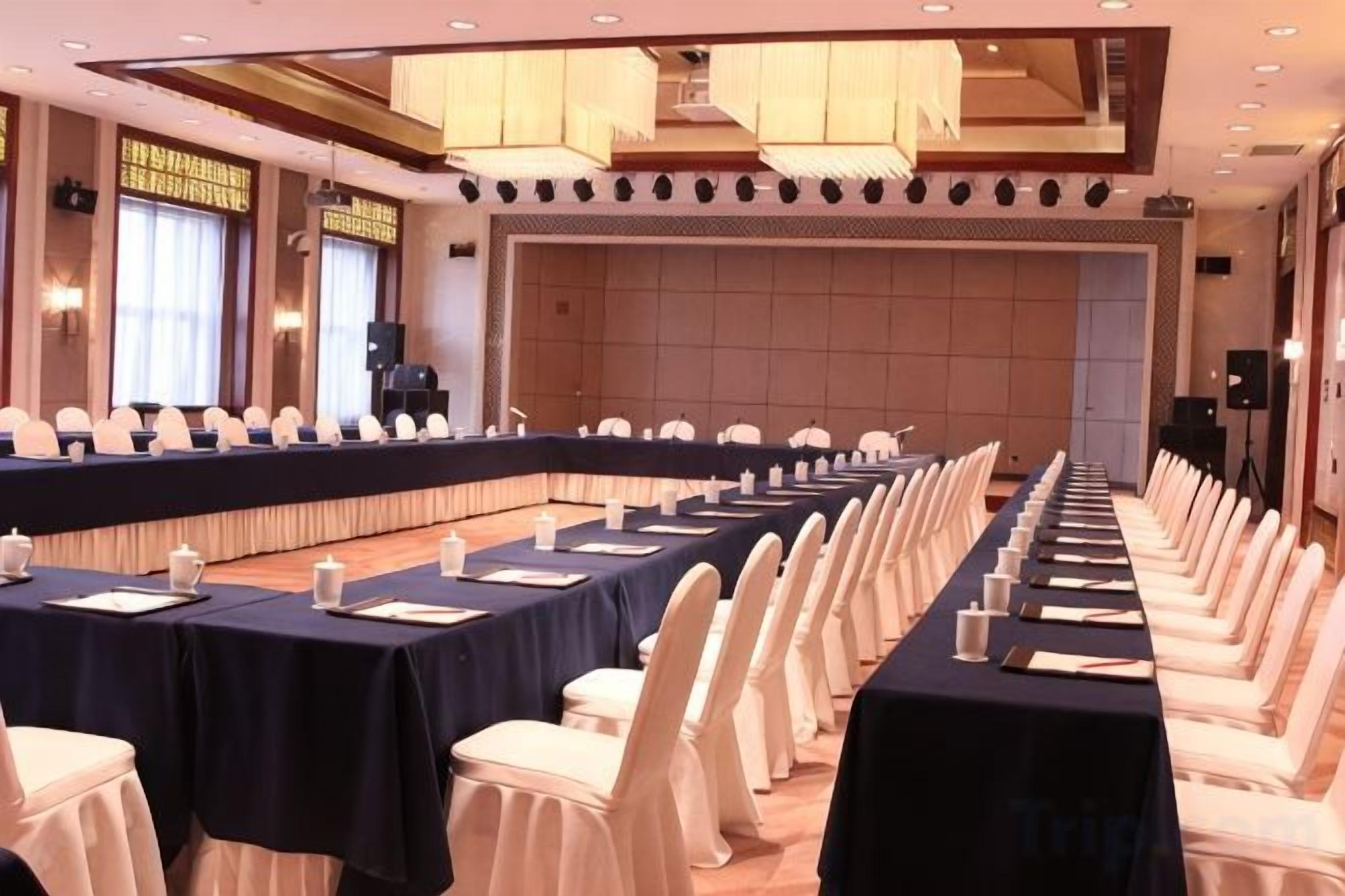 Una sala de conferencias con una larga mesa, sillas blancas y una zona de escenario.
