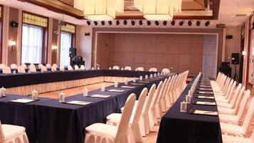 Una sala de conferencias con una larga mesa, sillas blancas y una zona de escenario.