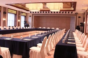 Una sala de conferencias con una larga mesa, sillas blancas y una zona de escenario.