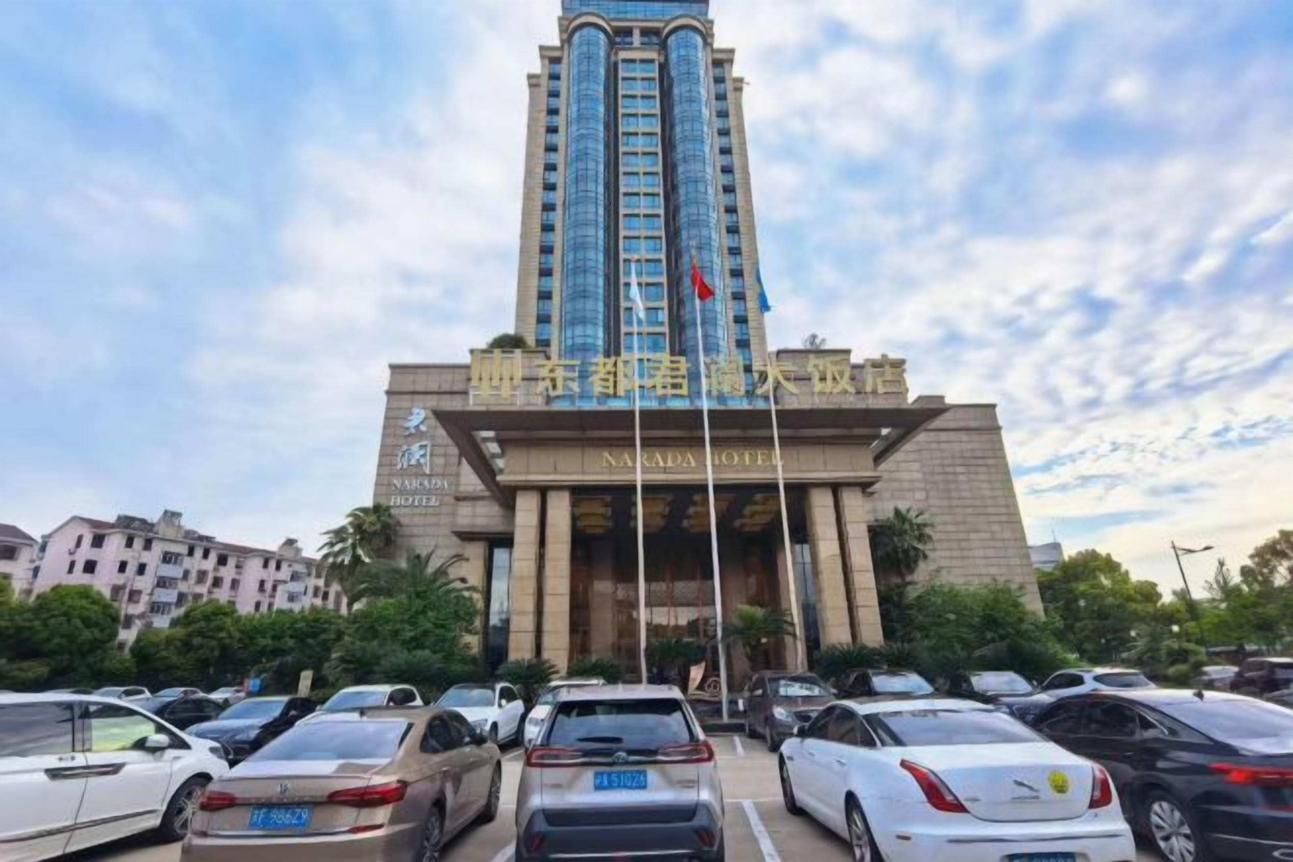 A hotel with a tall, modern building and a parking lot in front.