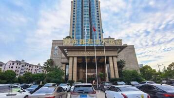 A hotel with a tall, modern building and a parking lot in front.