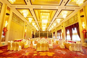 A banquet hall with round tables, white chairs, and a patterned carpet. - Dongdu Narada Grand Hotel (Yixing)