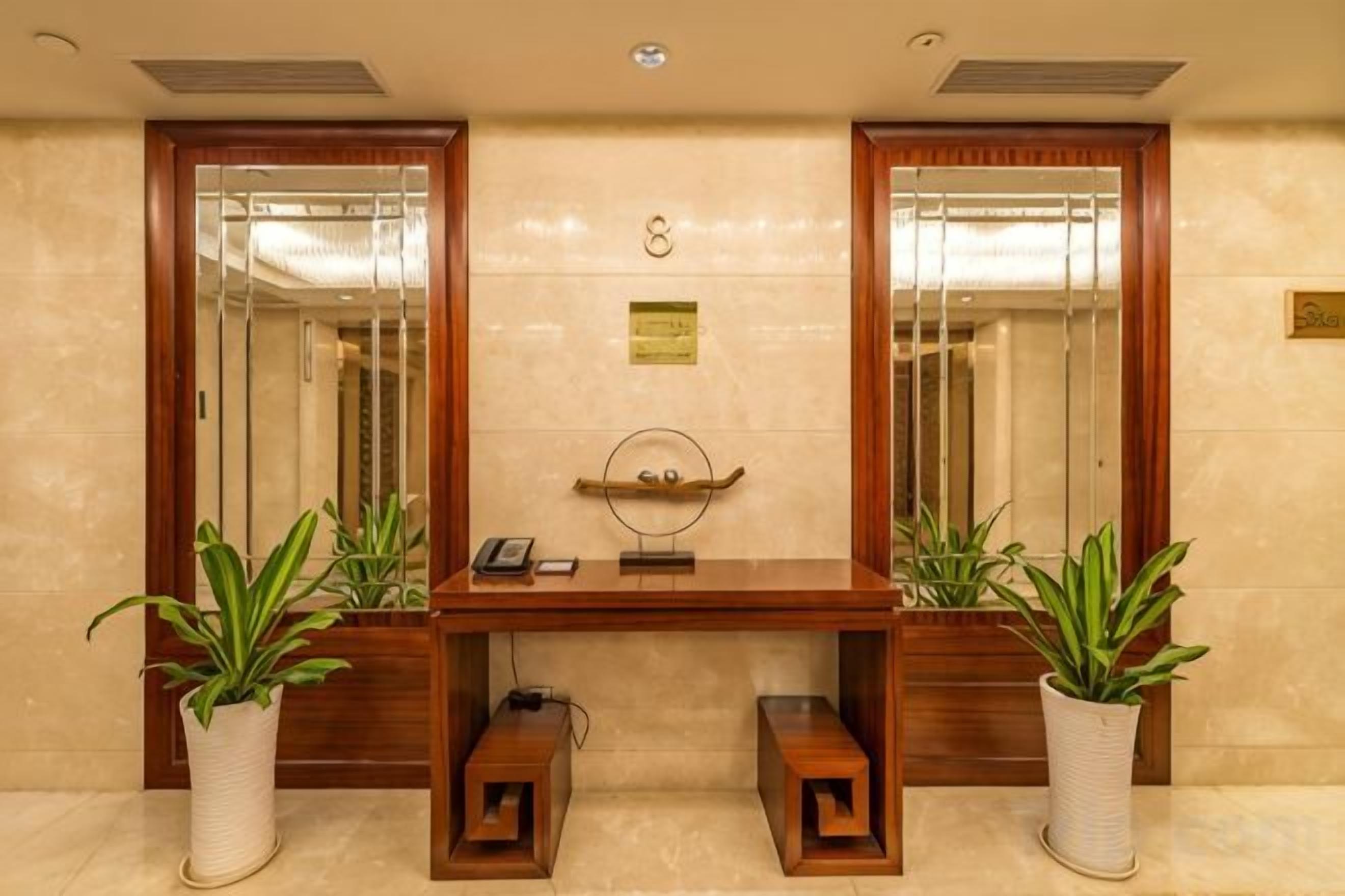 A reception desk with a telephone, a plaque, and two potted plants.
