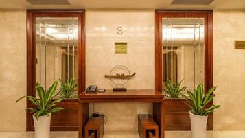 A reception desk with a telephone, a plaque, and two potted plants.