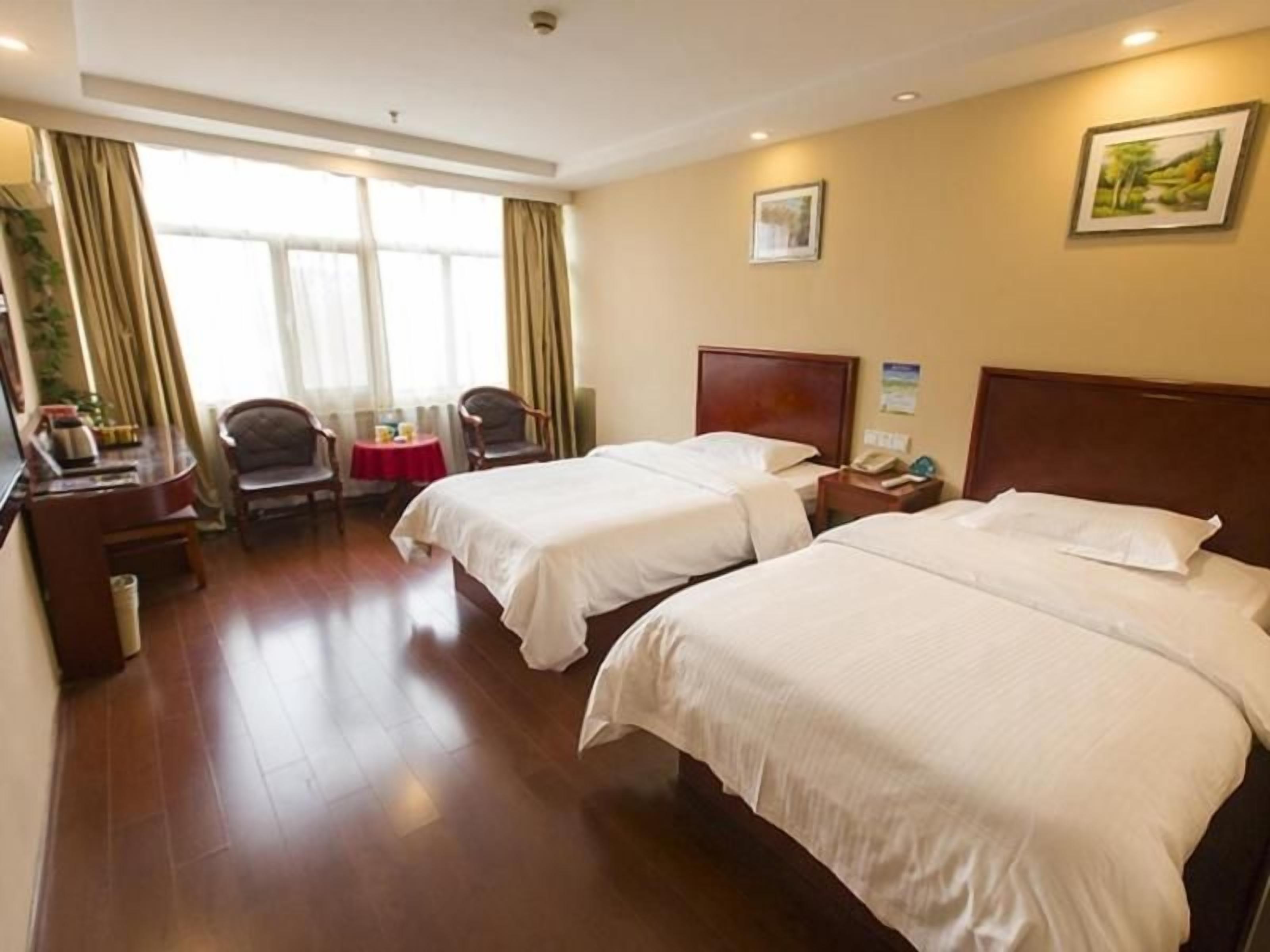 A hotel room with two beds, a desk, a chair, and a small table.