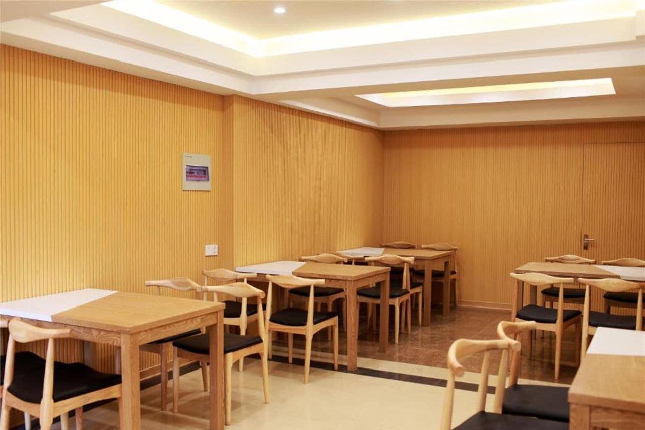 A hotel room with wooden panel walls, multiple wooden tables and chairs, and recessed ceiling lighting.