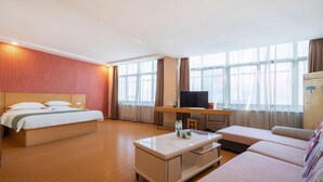 A hotel room with a bed, a desk with a TV, a sofa, and large windows. - Greentree Inn Shandong Linyi Yishui County Angel G (Linyi)