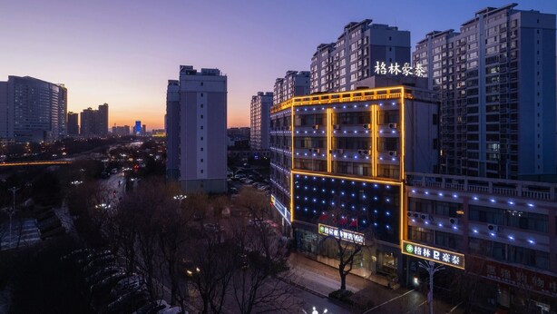 A multi-story building with illuminated windows and a sign indicating it is a hotel. - Greentree Inn Shandong Linyi Yishui County Angel G (Linyi)