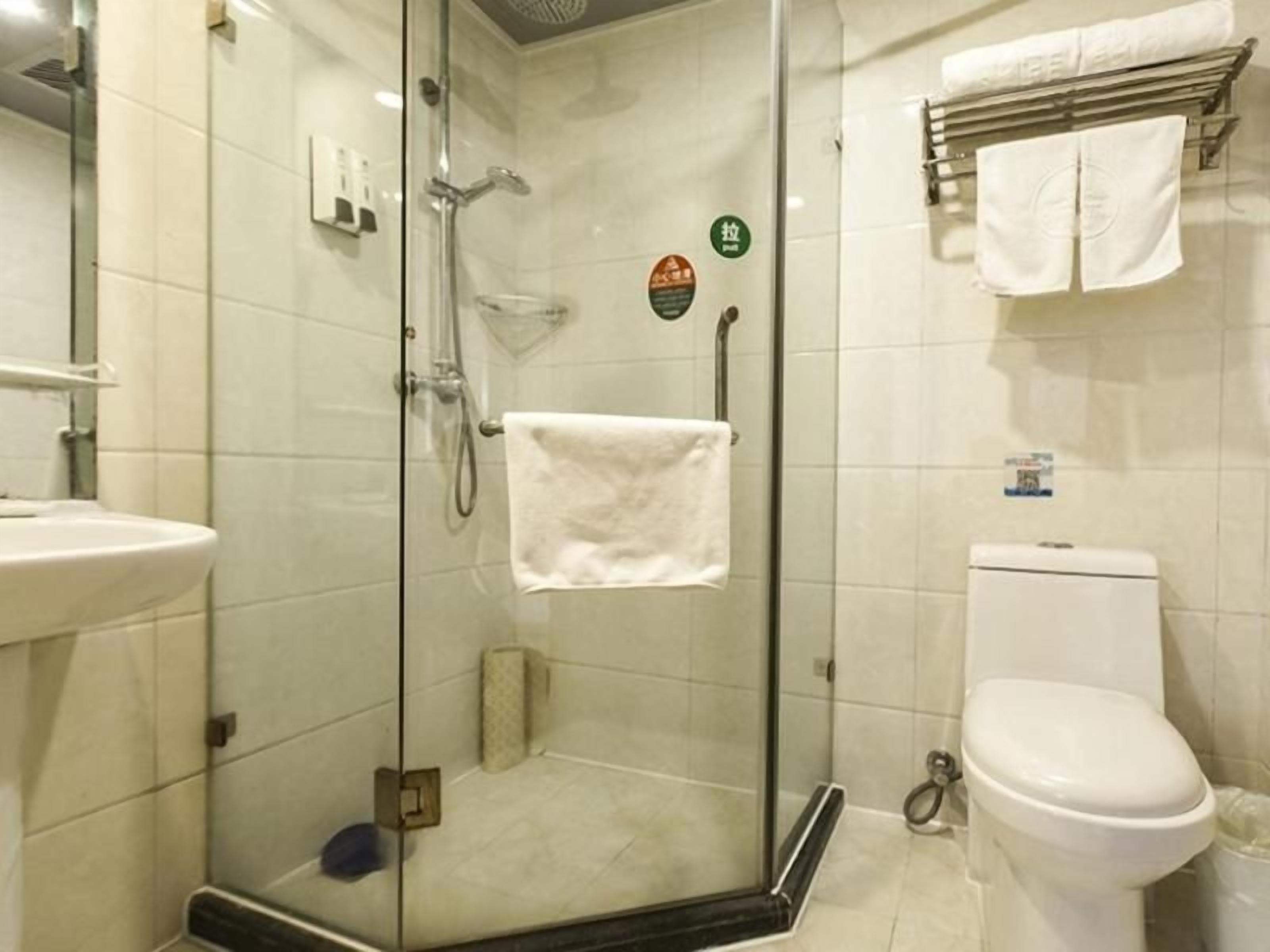 A bathroom with a glass-enclosed shower, a toilet, and a sink.